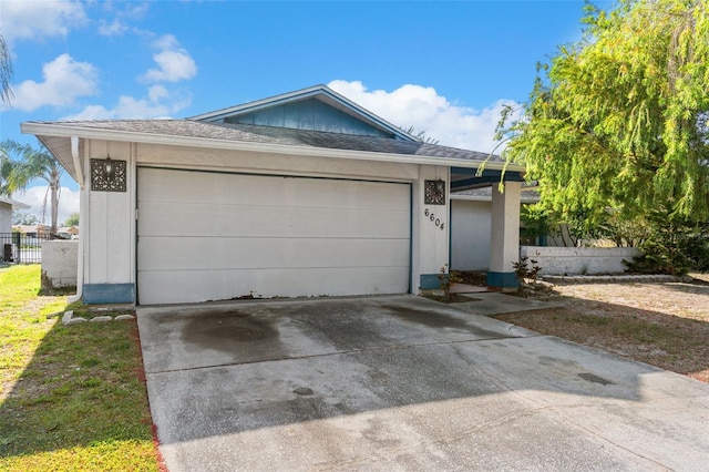 single story home featuring a garage, roof with shingles, fence, and driveway