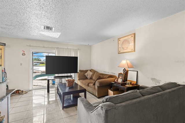 living room with a textured ceiling, visible vents, and light tile patterned floors