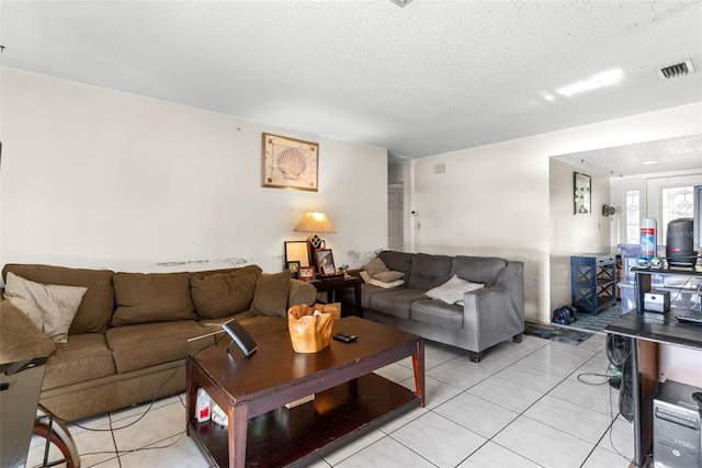 living room with light tile patterned floors, a textured ceiling, and visible vents