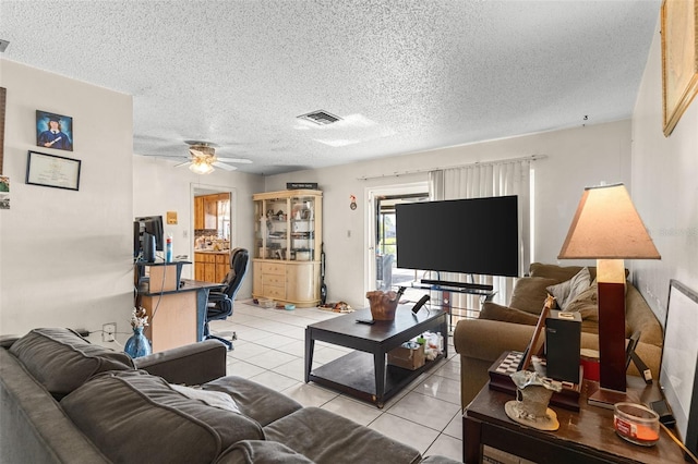 living area featuring light tile patterned flooring, a textured ceiling, visible vents, and ceiling fan