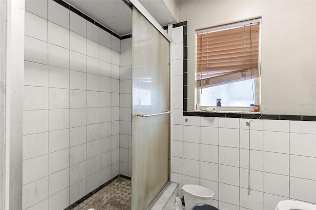full bath with a stall shower, toilet, and tile walls