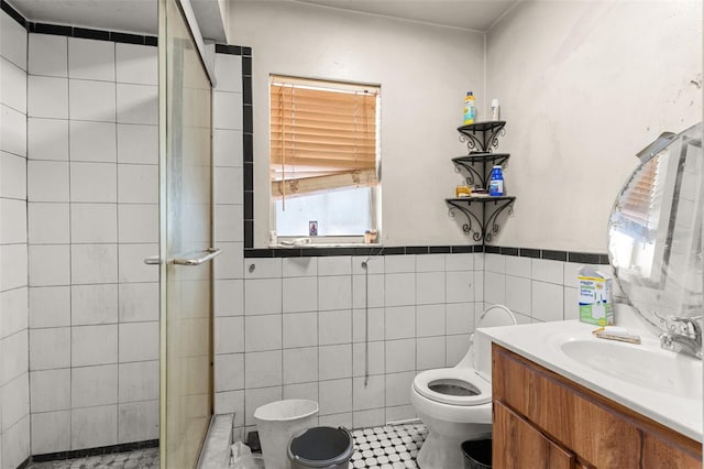 bathroom featuring tile walls, tile patterned flooring, a stall shower, vanity, and toilet