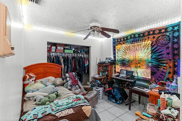 bedroom with tile patterned floors, ceiling fan, a closet, and a textured ceiling