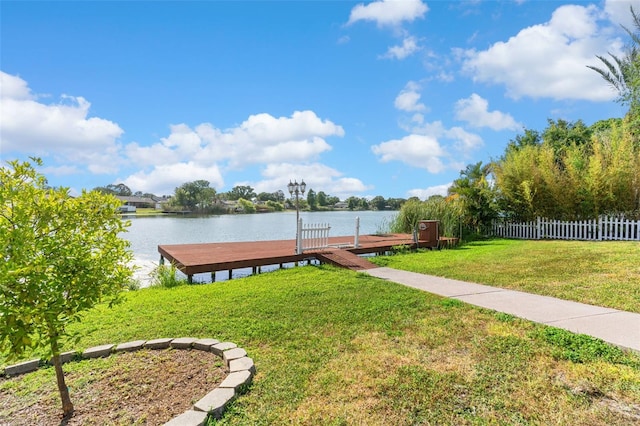 dock area featuring a lawn, a water view, and fence