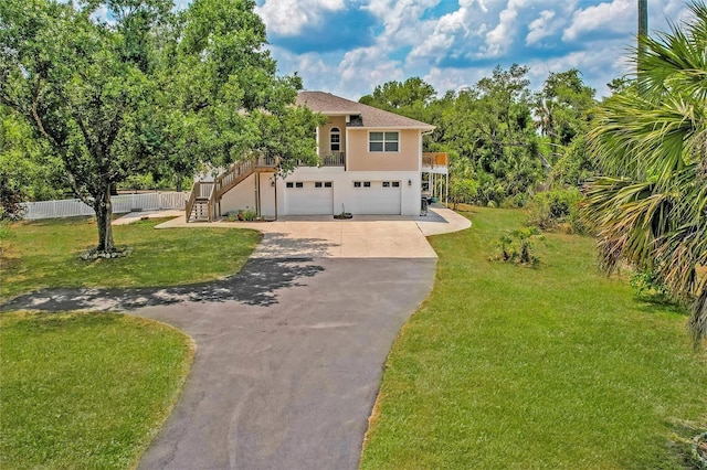 view of front of house featuring an attached garage, driveway, and a front lawn