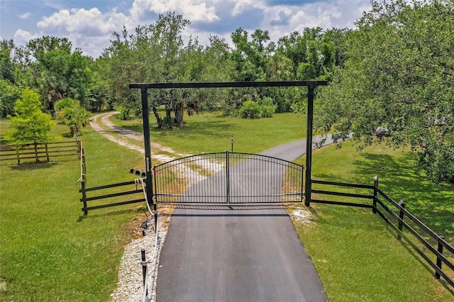 view of gate featuring a lawn and fence