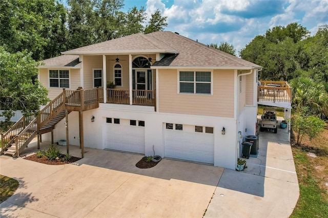 view of front of property with a ceiling fan, roof with shingles, concrete driveway, an attached garage, and stairs