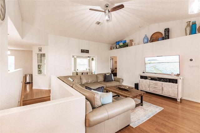 living area with visible vents, wood finished floors, baseboards, a ceiling fan, and vaulted ceiling