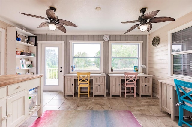 interior space with ceiling fan, wood walls, a wealth of natural light, and open shelves