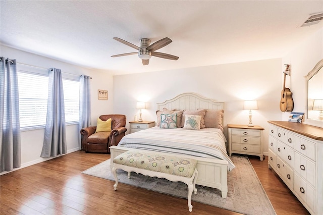 bedroom with baseboards, ceiling fan, visible vents, and wood finished floors