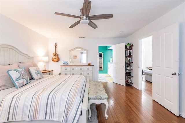 bedroom featuring ceiling fan, multiple windows, visible vents, wood finished floors, and ensuite bath