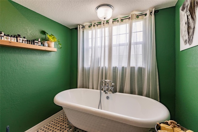 bathroom featuring baseboards, a textured wall, and a wealth of natural light
