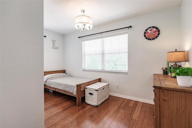 bedroom featuring an inviting chandelier, baseboards, and wood finished floors