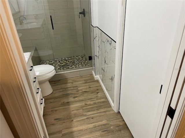 full bathroom with a stall shower, toilet, and wood finished floors