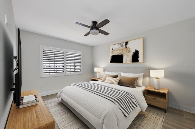 bedroom with a ceiling fan, baseboards, and wood finished floors