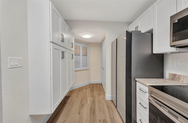 kitchen with appliances with stainless steel finishes, light countertops, baseboards, white cabinets, and light wood-style floors