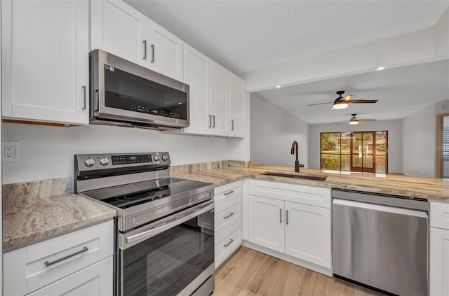 kitchen with ceiling fan, white cabinetry, a sink, light wood-style flooring, and appliances with stainless steel finishes