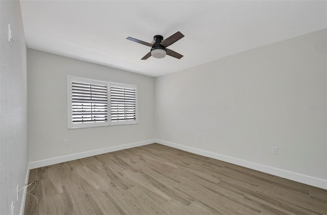 spare room with baseboards, ceiling fan, and wood finished floors