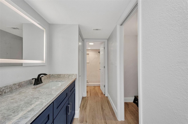 full bath with visible vents, a stall shower, wood finished floors, and vanity