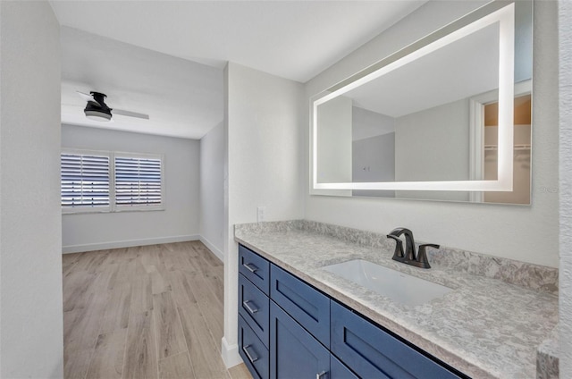 bathroom with baseboards, wood finished floors, and vanity