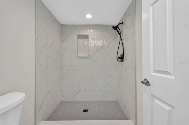 bathroom featuring a marble finish shower and toilet