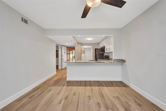 kitchen featuring baseboards, a peninsula, light wood-style flooring, and visible vents