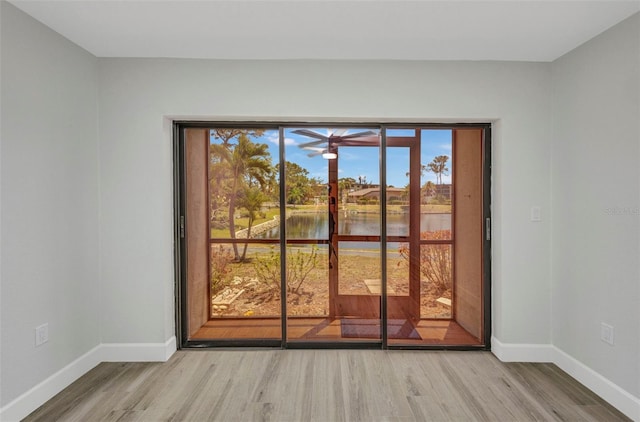 doorway to outside featuring a water view, baseboards, and light wood-style flooring