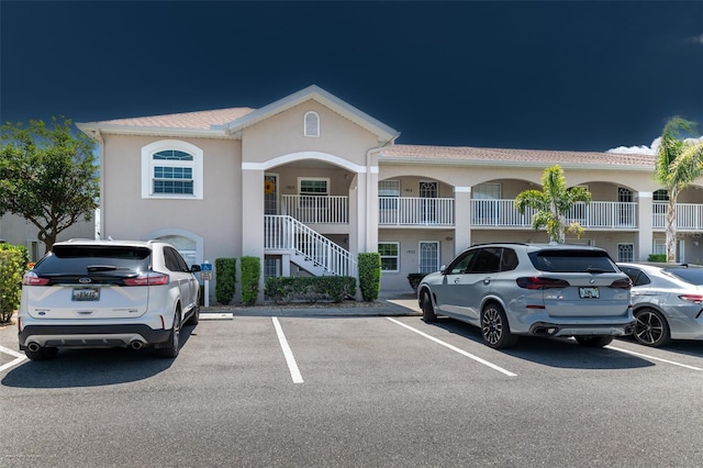 view of property with uncovered parking and stairs