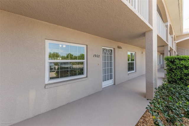 view of exterior entry featuring a patio and stucco siding