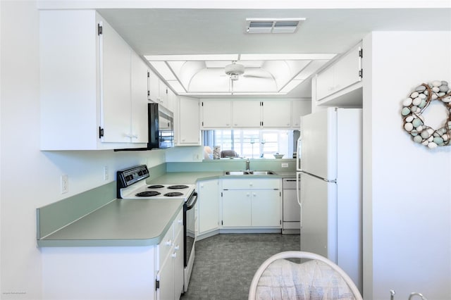 kitchen featuring a sink, white cabinets, visible vents, a raised ceiling, and white appliances