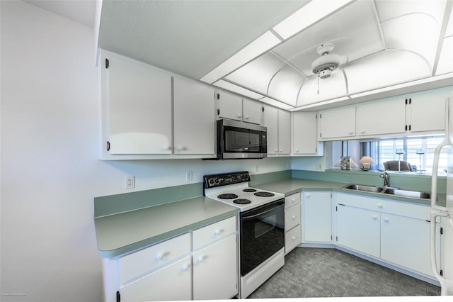 kitchen with stainless steel microwave, a sink, light countertops, white electric stove, and white cabinets