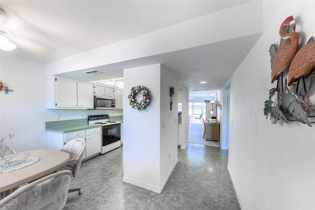 kitchen with stainless steel microwave, baseboards, visible vents, and electric range