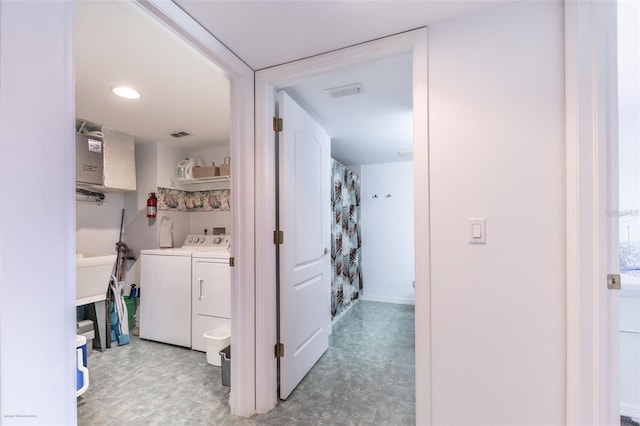 corridor with separate washer and dryer, light floors, and visible vents