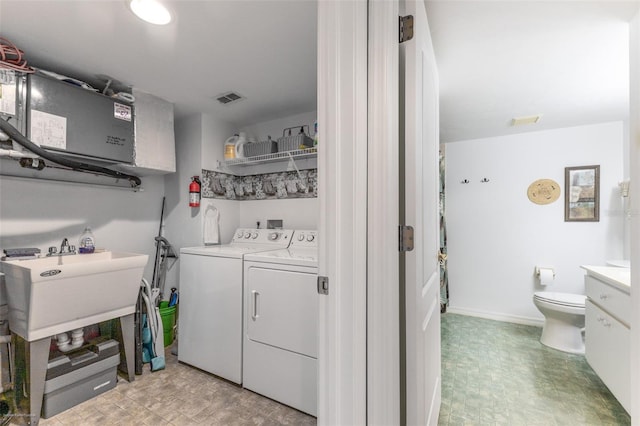 washroom featuring washer and clothes dryer, laundry area, a sink, and visible vents