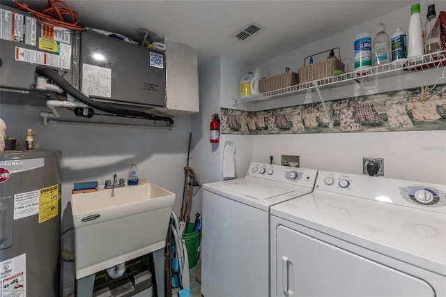 laundry area with laundry area, water heater, a sink, and washing machine and clothes dryer
