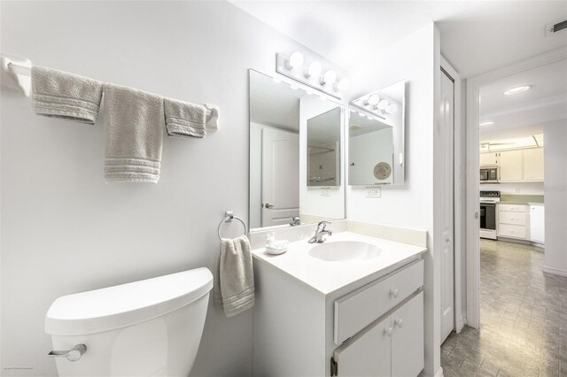 bathroom featuring toilet, vanity, and recessed lighting