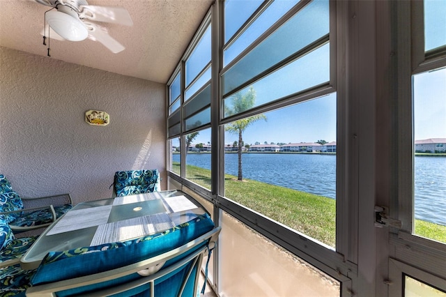 sunroom / solarium with ceiling fan and a water view