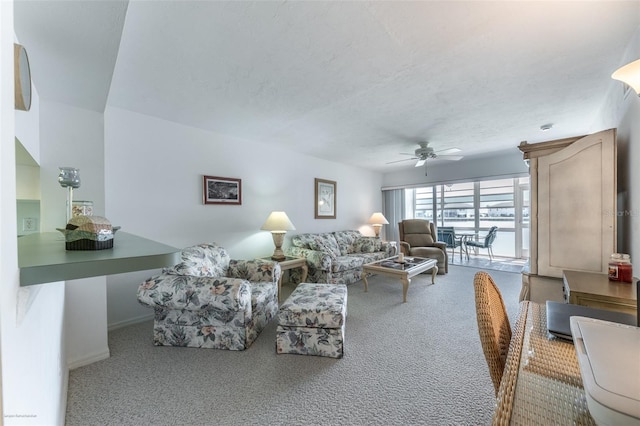 carpeted living room with a textured ceiling, baseboards, and a ceiling fan