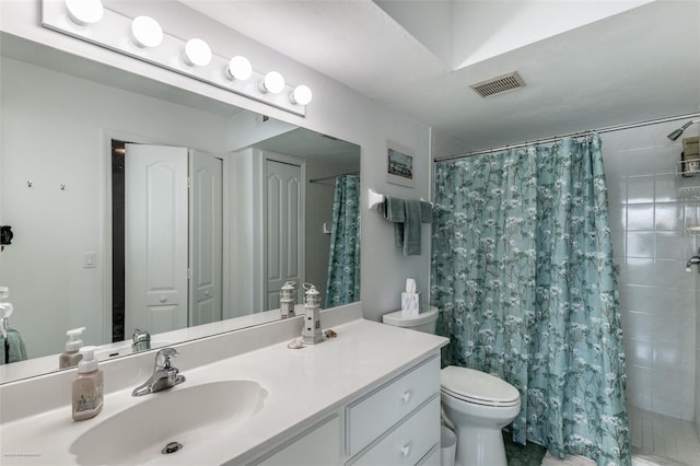bathroom with vanity, toilet, visible vents, and a tile shower