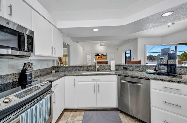 474 Lomond Dr, Port Charlotte, FL 33953 - kitchen with stainless steel appliances, a sink, dark stone counters, white cabinetry, and lofted ceiling