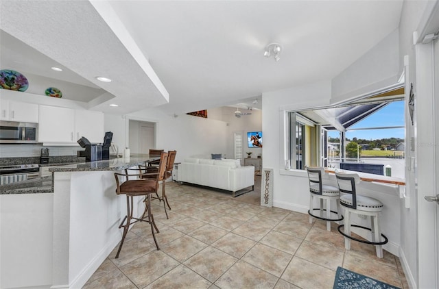 474 Lomond Dr, Port Charlotte, FL 33953 - kitchen with appliances with stainless steel finishes, a kitchen bar, dark stone countertops, white cabinets, and light tile patterned floors