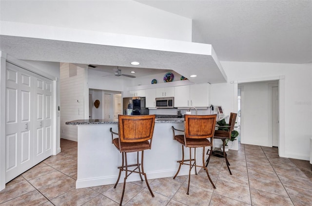 474 Lomond Dr, Port Charlotte, FL 33953 - kitchen with stainless steel microwave, a peninsula, white cabinetry, freestanding refrigerator, and light tile patterned floors