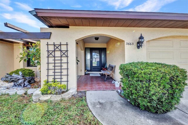 view of exterior entry featuring a garage and stucco siding