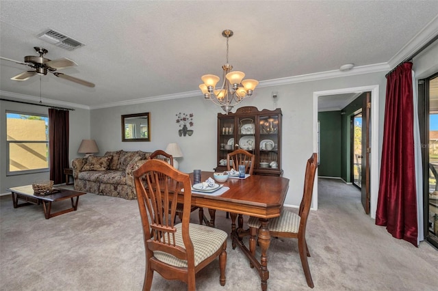 dining area featuring a textured ceiling, visible vents, crown molding, ceiling fan with notable chandelier, and light carpet