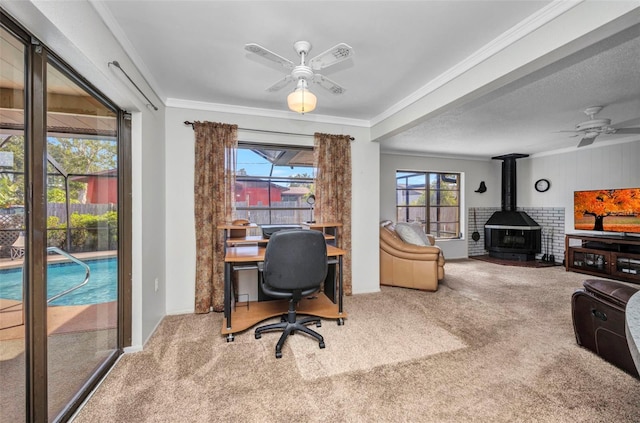 carpeted office with crown molding, a ceiling fan, and a wood stove