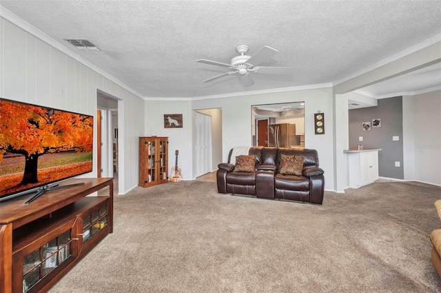living room with visible vents, ornamental molding, ceiling fan, a textured ceiling, and carpet flooring
