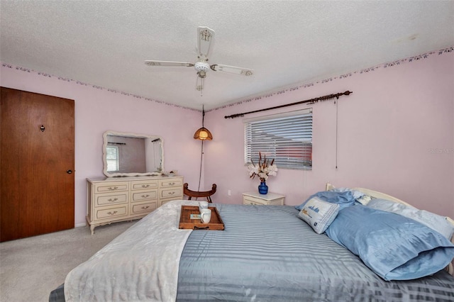 bedroom with baseboards, a textured ceiling, light carpet, and ceiling fan