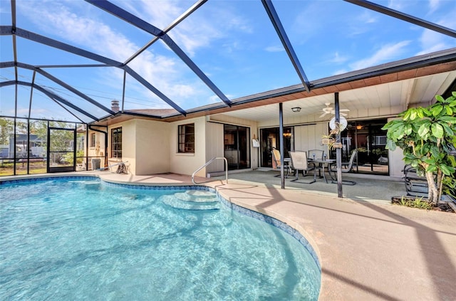 outdoor pool with glass enclosure, a patio, and a ceiling fan