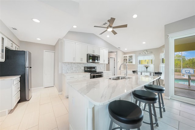kitchen with a sink, appliances with stainless steel finishes, ceiling fan, white cabinets, and a breakfast bar area