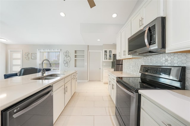 kitchen with appliances with stainless steel finishes, a sink, light countertops, white cabinetry, and recessed lighting